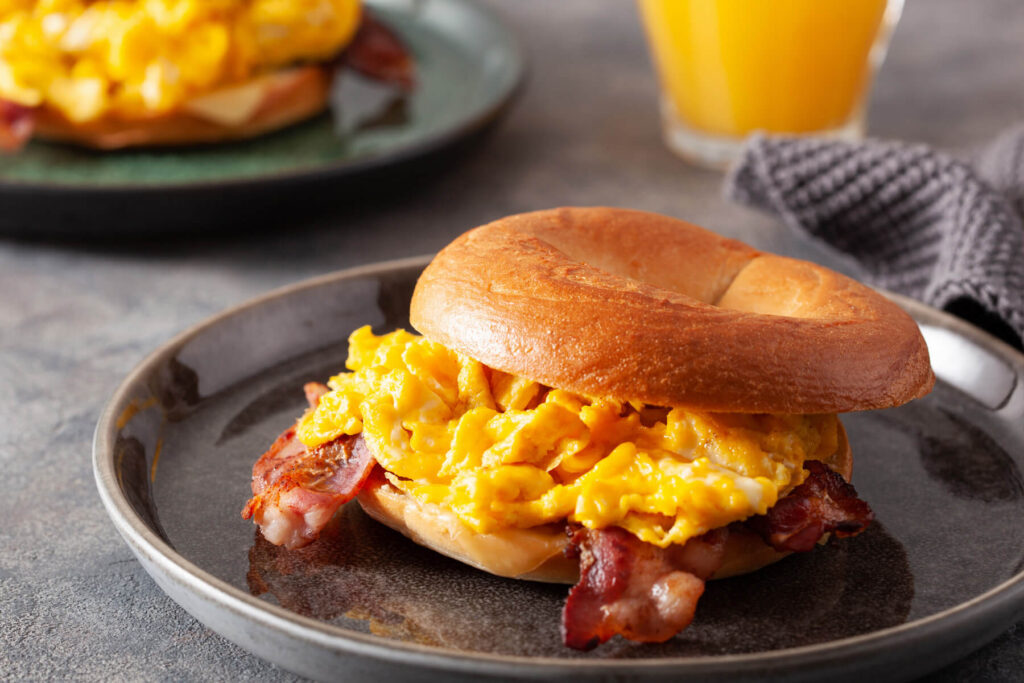 Bagel-Frühstücks-Sandwich mit Rührei, Bacon & Käse