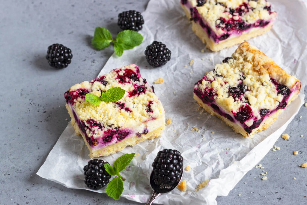 Zitronen-Cheesecake-Schnitten mit schwarzen Johannisbeeren & Streuseln
