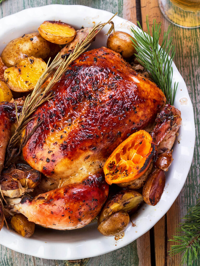 Ganzes Brathähnchen aus dem Ofen mit Kartoffeln und Mandarinen
