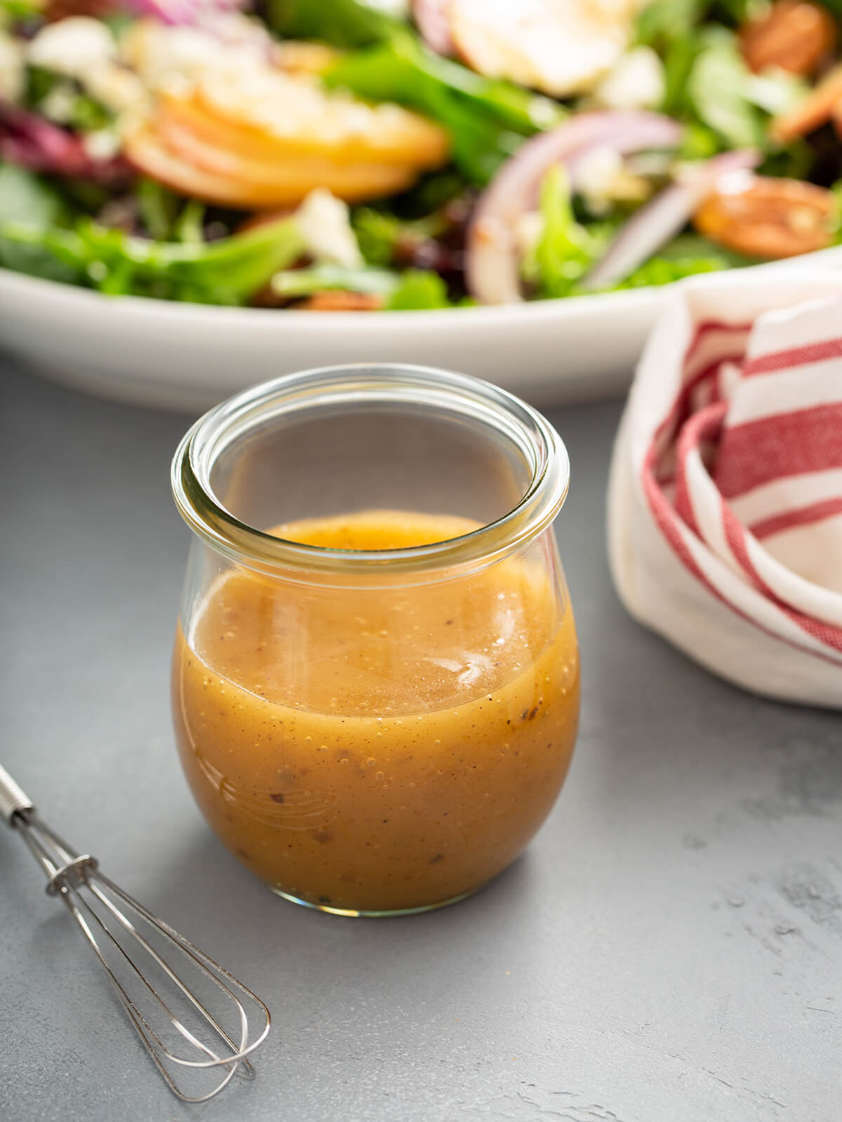 Apfel-Vinaigrette im Glas neben Herbstsalat mit Apfel und Walnüssen
