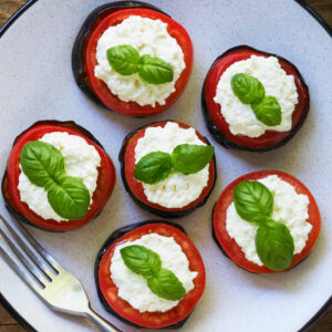 Gebratene Auberginen mit Tomate und Frischkäse auf Teller