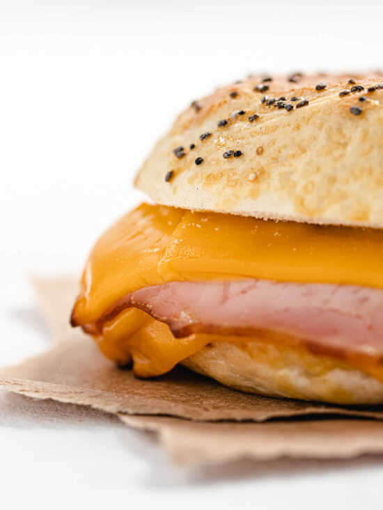 Bagel mit Cheddar und Schinken angeschnitten mit Mohn- und Sesam-Bestreuung