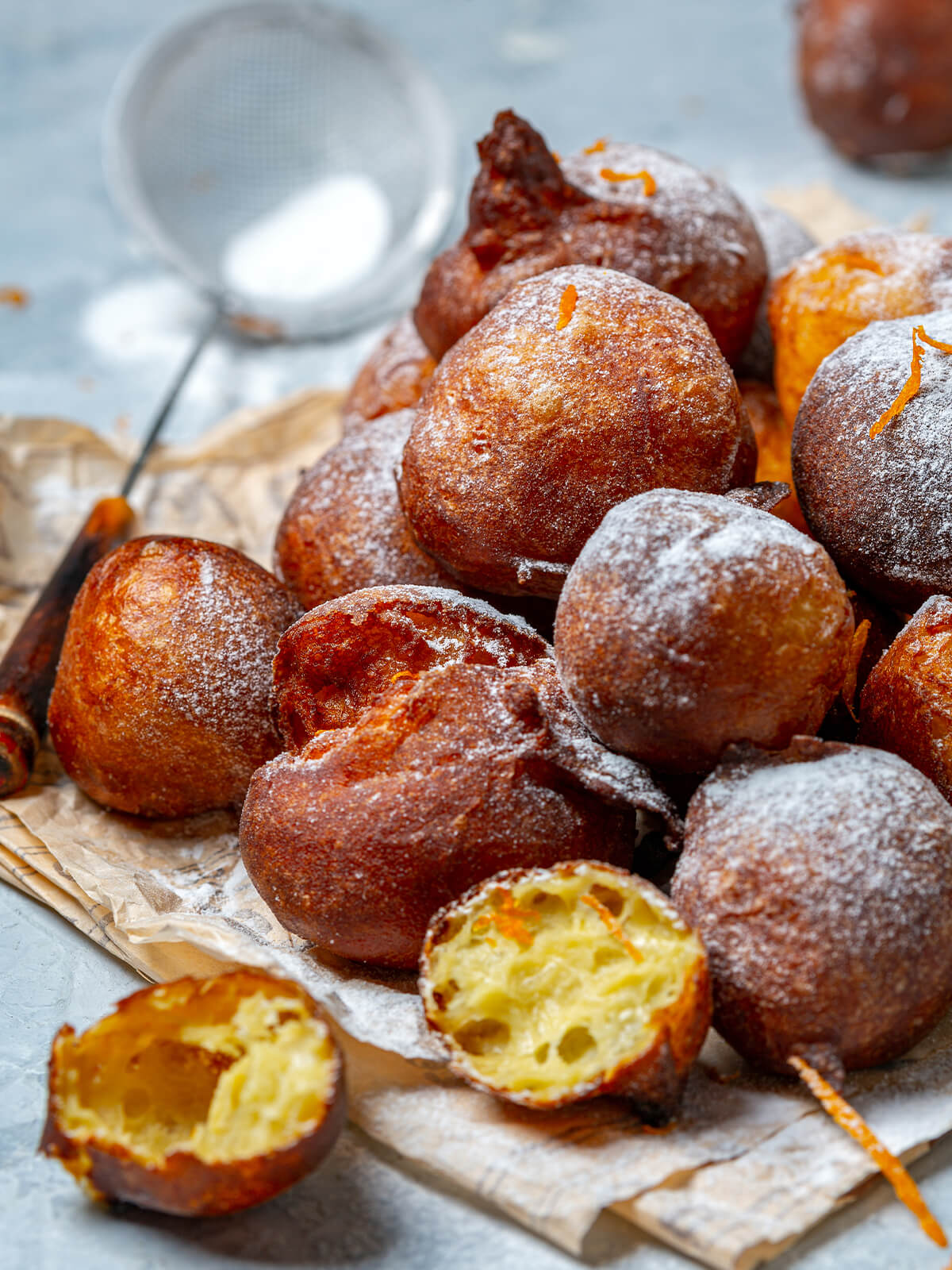 Aufgeschnittene französische Beignets aus Brandteig mit hohler, luftiger Krume und Puderzucker