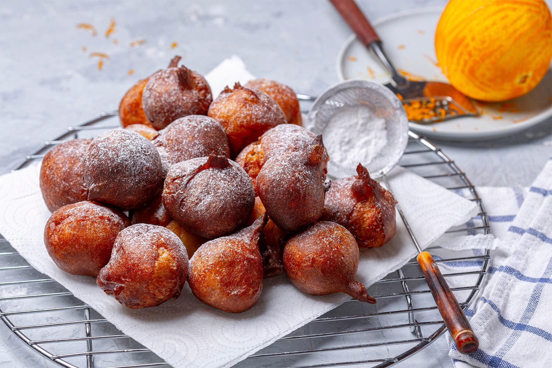 Französische Beignets mit Puderzucker und frischen Orangen und Zitronen für die Zesten