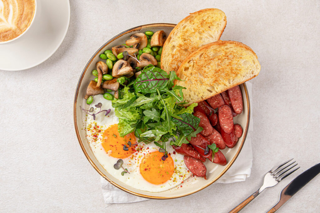 English Breakfast Bowl mit Spiegelei, Würstchen und Salat
