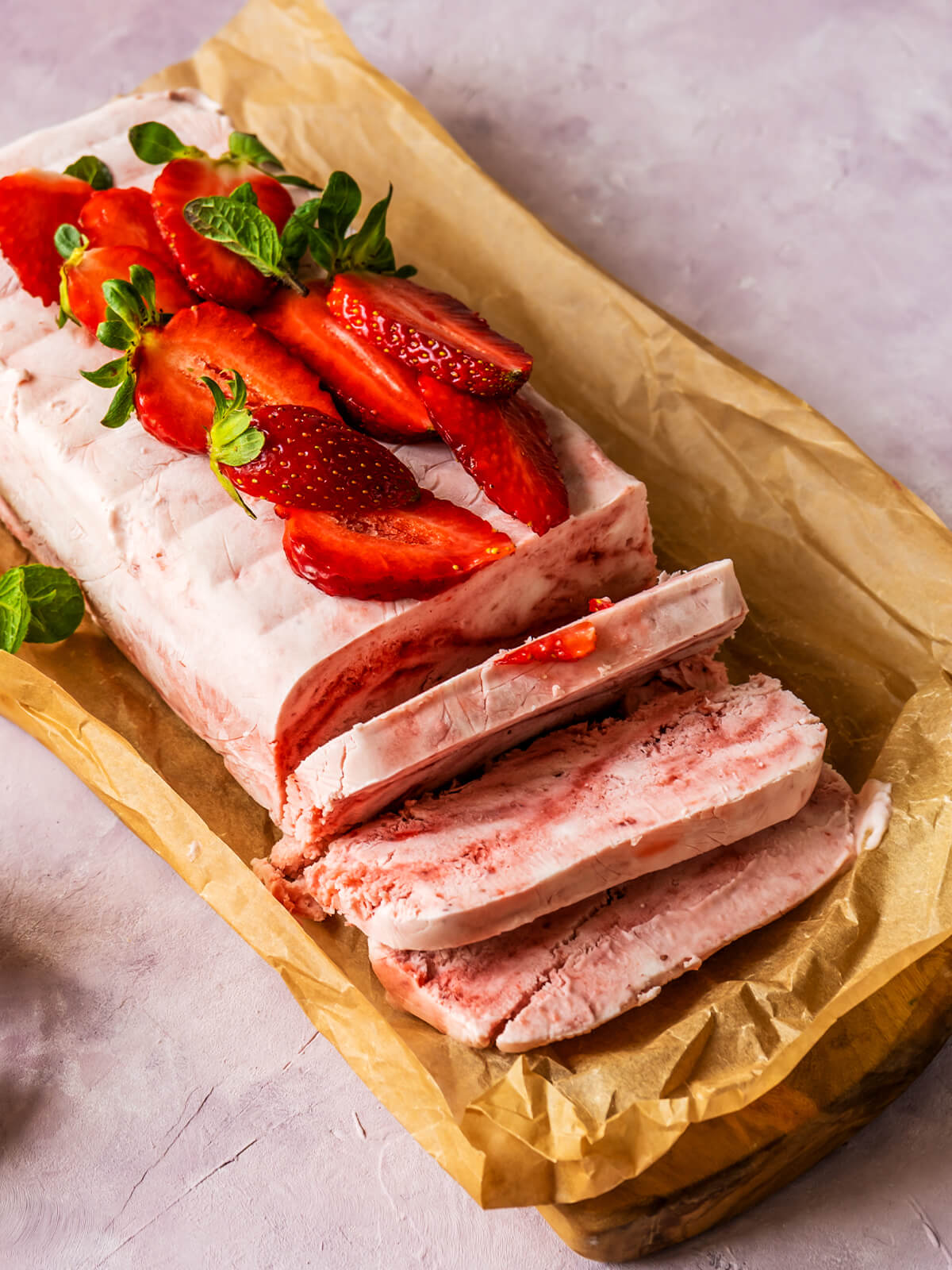 Erdbeer-Semifreddo in Scheiben geschnitten mit feinen Erdbeer-Schlieren, garniert mit frischen Erdbeeren und Minze