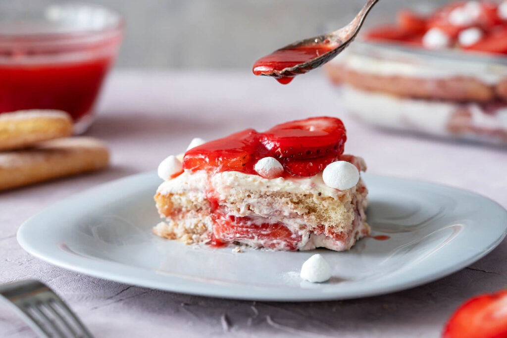 Erdbeer-Tiramisu mit frischen Erdbeeren und kleinen Baiser-Tupfen, geschichtet in einer Glasform
