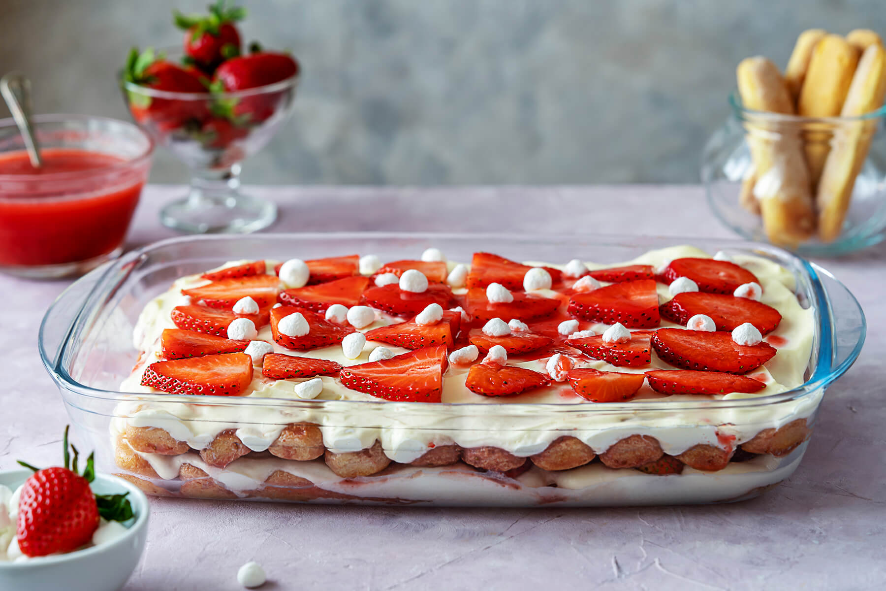 Erdbeer-Tiramisu in der Glasform, dekoriert mit Erdbeerscheiben und kleinen Baiser-Tupfen