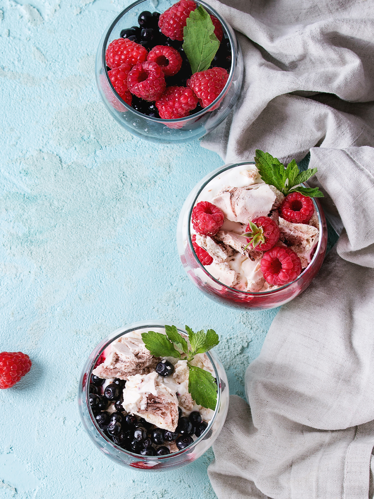 Eton Mess festlich angerichtet mit gemischten Beeren und Minzblättern
