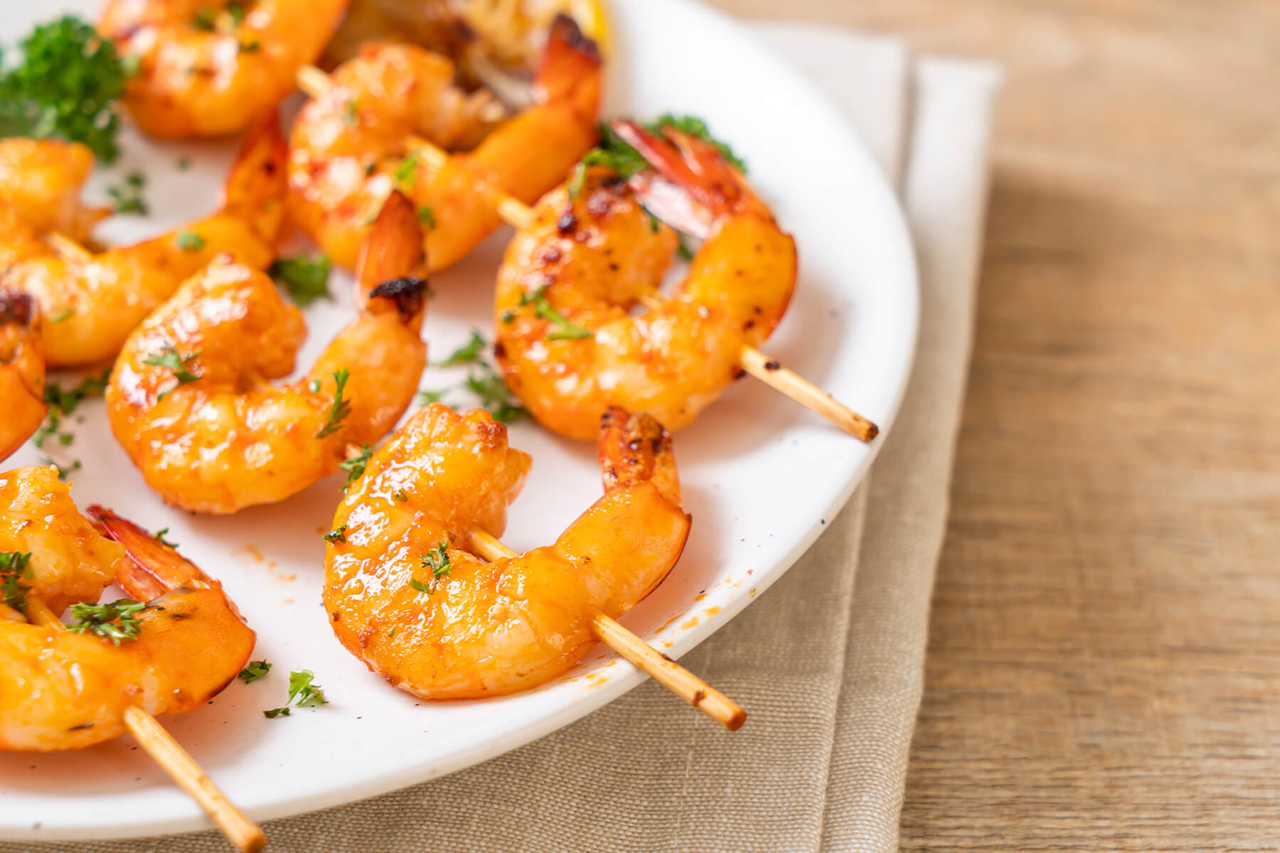 Goldorange gegrillte Tiger-Garnelen am Holzspieß mit Petersilie