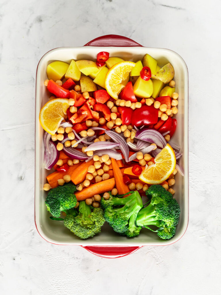 Rohes Gemüse für die Bowl in einer Auflaufform – Kartoffelstücke mit Schale, Paprika, Kichererbsen, Möhrenstifte, rote Zwiebel, Brokkoli und Zitronenscheiben