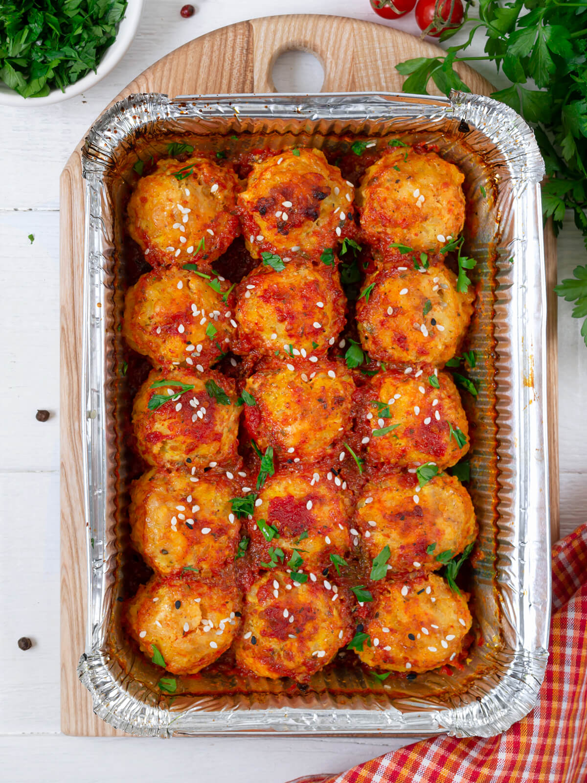Hähnchen-Bällchen in Tomatensauce mit weißem und schwarzem Sesam und Petersilie
