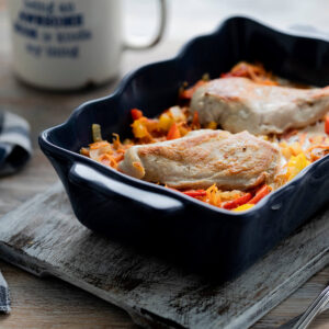 Hähnchenfilet mit Paprika und geriebenen Möhren in dunkelblauer Keramikform