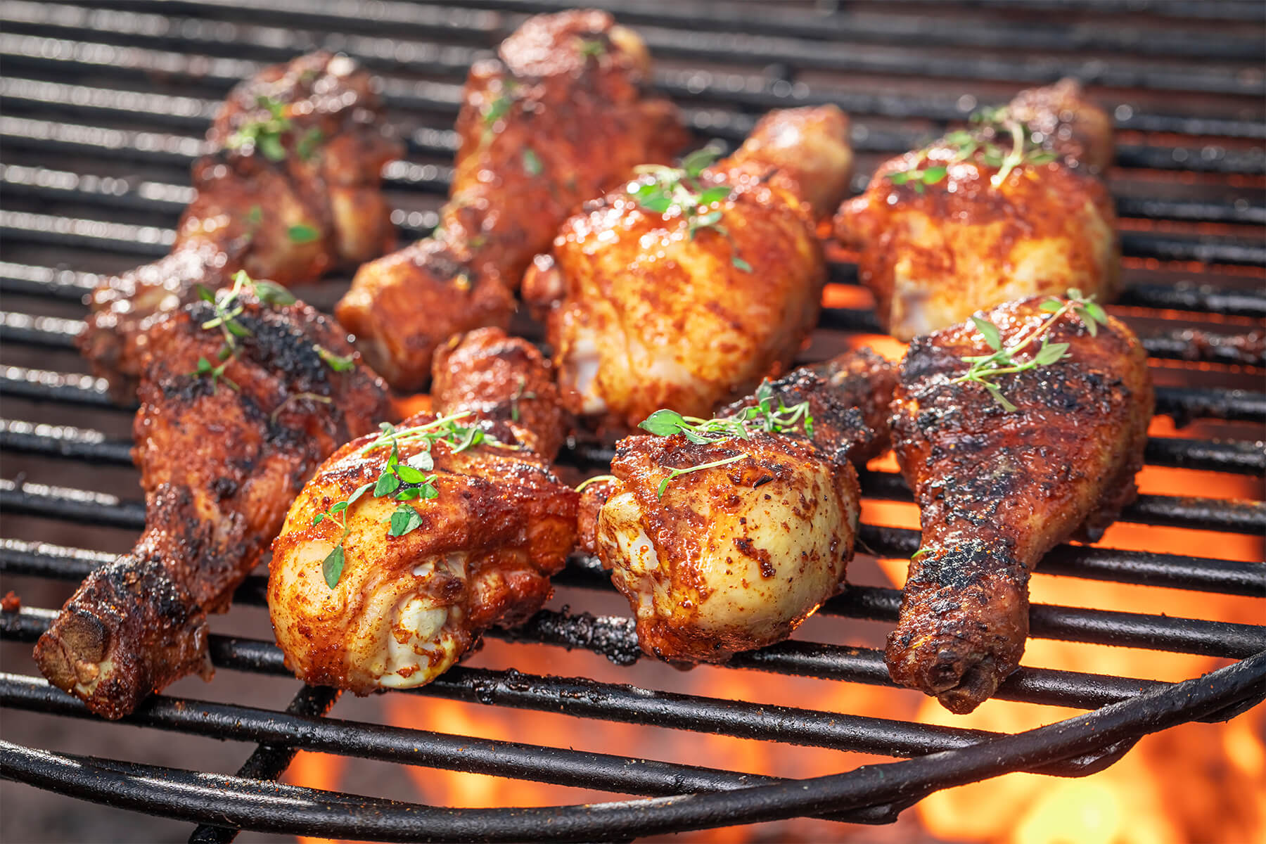 Marinierte Hähnchenschenkel mit Honig-Paprika-Marinade auf dem Grillrost über der Glut