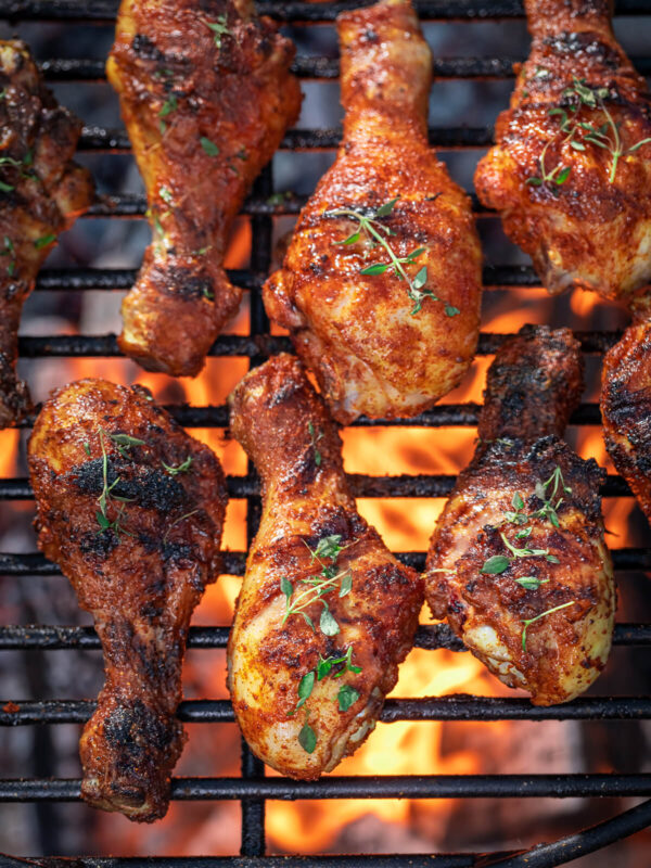 Gegrillte Hähnchenschenkel mit karamellisierter Honig-Paprika-Glasur und Thymian auf dem Grillrost