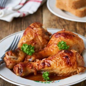Hähnchenschenkel in Paprika-Sauce auf weißem Teller
