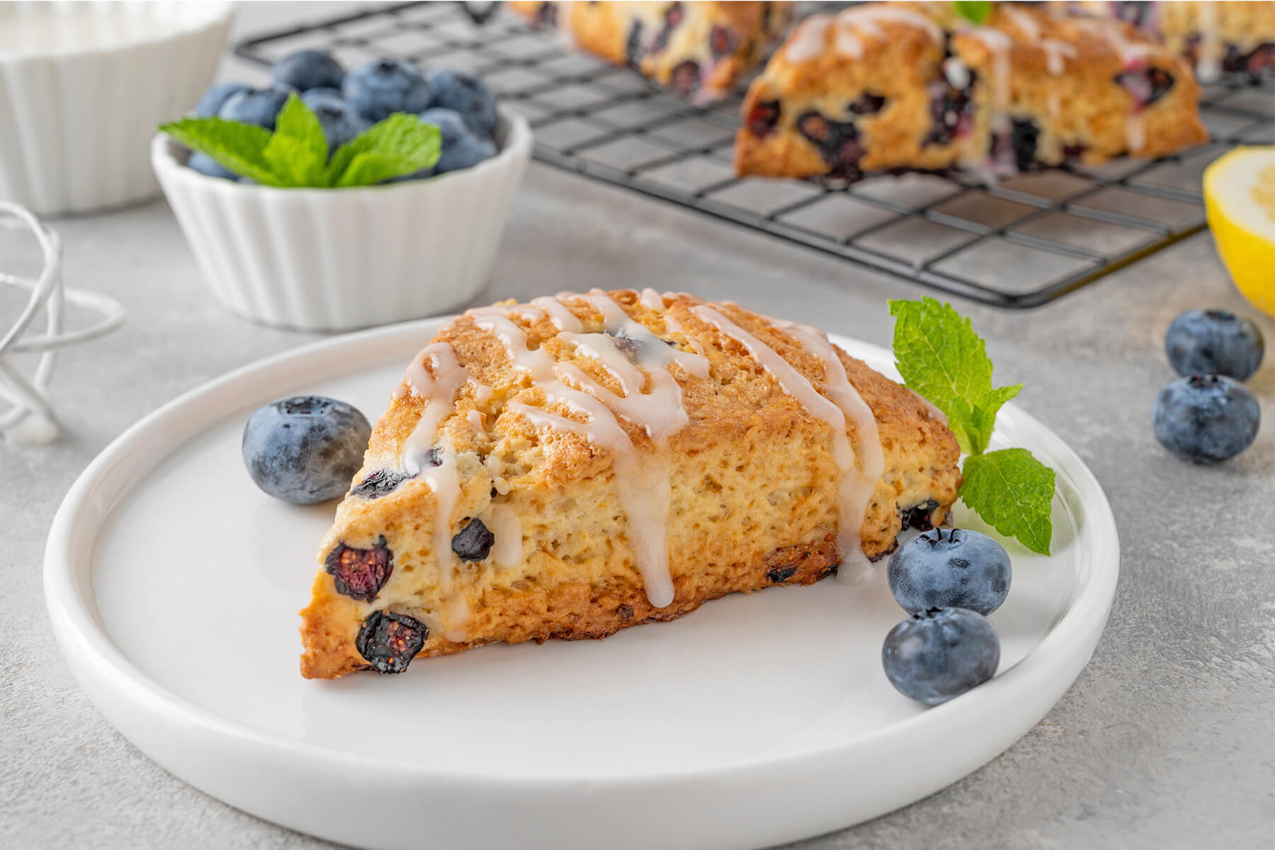 Dreieckiger Heidelbeer-Scone mit Zitronenglasur und violetten Saftschlieren in der hellen Krume