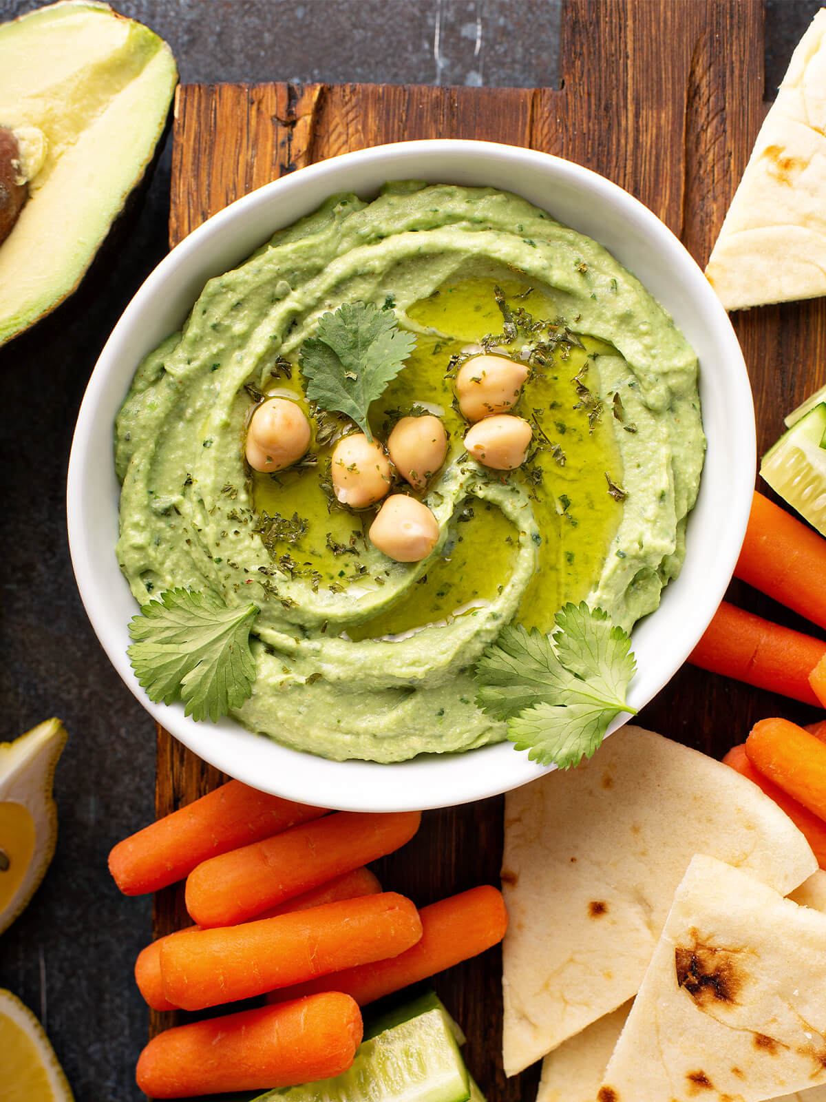 Cremiger grüner Hummus mit Avocado in Schale, dekoriert mit Olivenöl und Kichererbsen