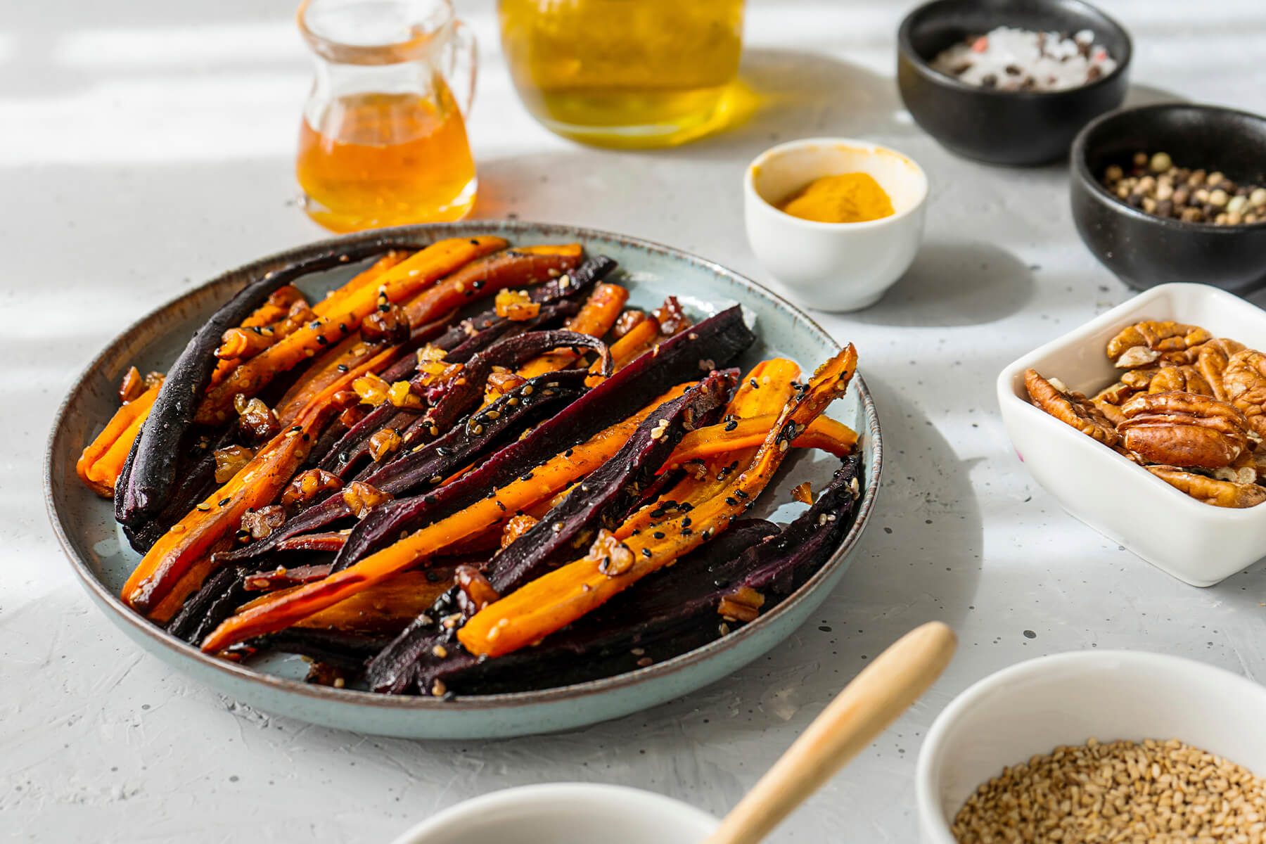 Marokkanische glasierte orange und violette Karotten mit Honig, Pekannüssen und Sesam, dazu Honig und Olivenöl