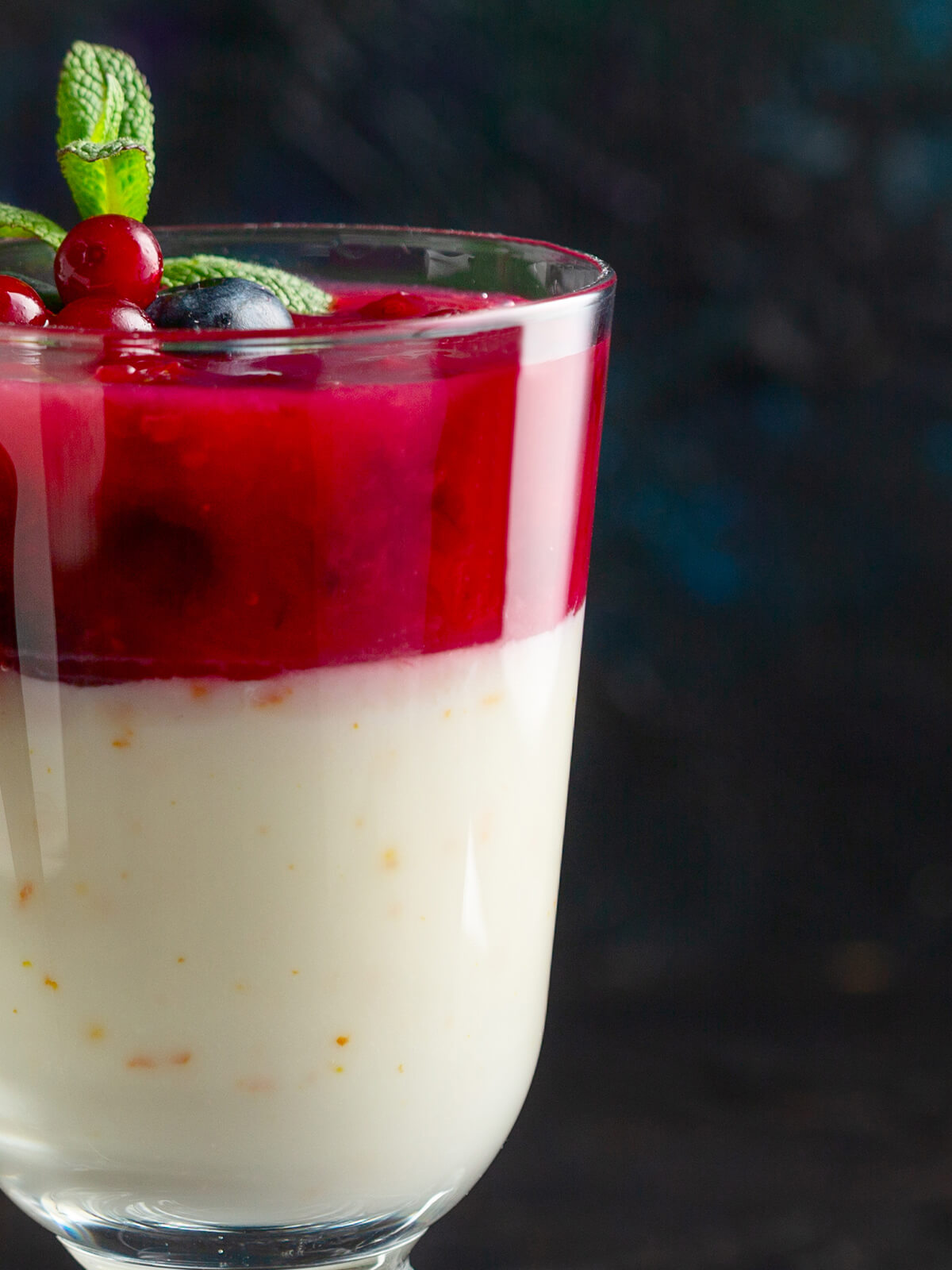 Zweischichtiger Milchpudding mit Preiselbeeren im Glas, weiße Schicht unten, rote Beerenschicht oben