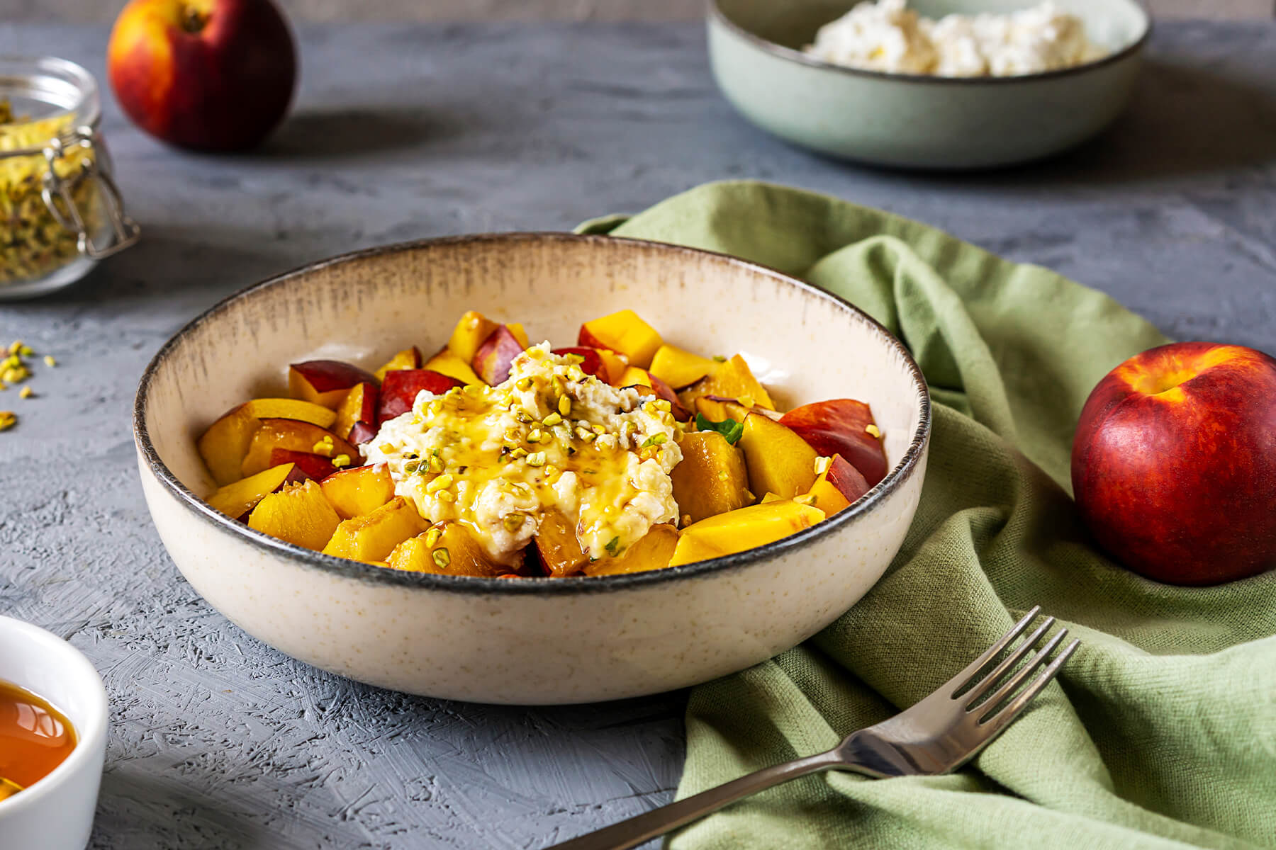 Nektarinen-Ricotta-Salat in Keramikschale mit gewürfelten Nektarinen, Ricotta-Creme, Pistazien und Honig