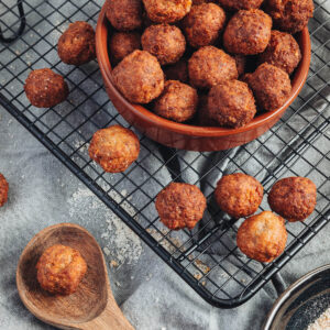 Goldbraune frittierte Polpette al Parmigiano in terracotta-farbener Schale auf Kühlrost als italienisches Antipasto