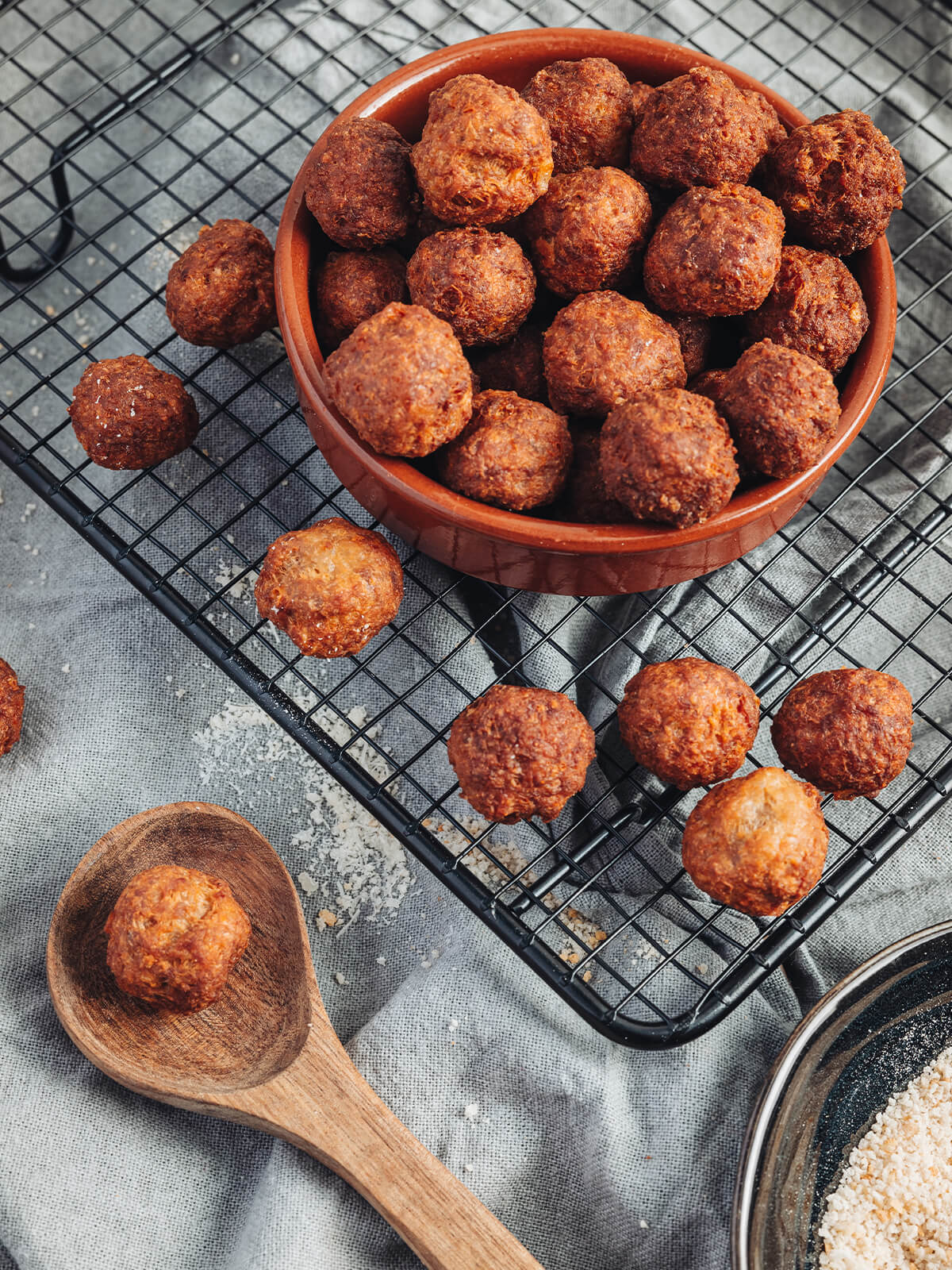 Goldbraune frittierte Polpette al Parmigiano in terracotta-farbener Schale auf Kühlrost als italienisches Antipasto