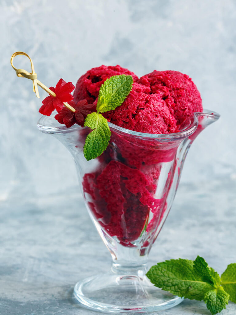 Tiefrotes Rote-Bete-Sorbet in Glasbecher mit frischer Minze und Beerendekor