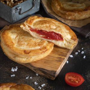 Aufgebrochenes Rustico Leccese mit dicker roter Tomatenschicht und cremiger Käseschicht auf dünnem Blätterteigboden