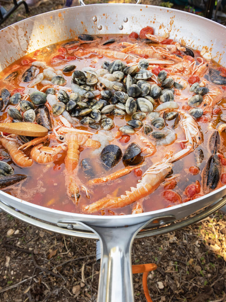 Große Pfanne mit Meeresfrüchten im Tomatensud im Freien beim Garen