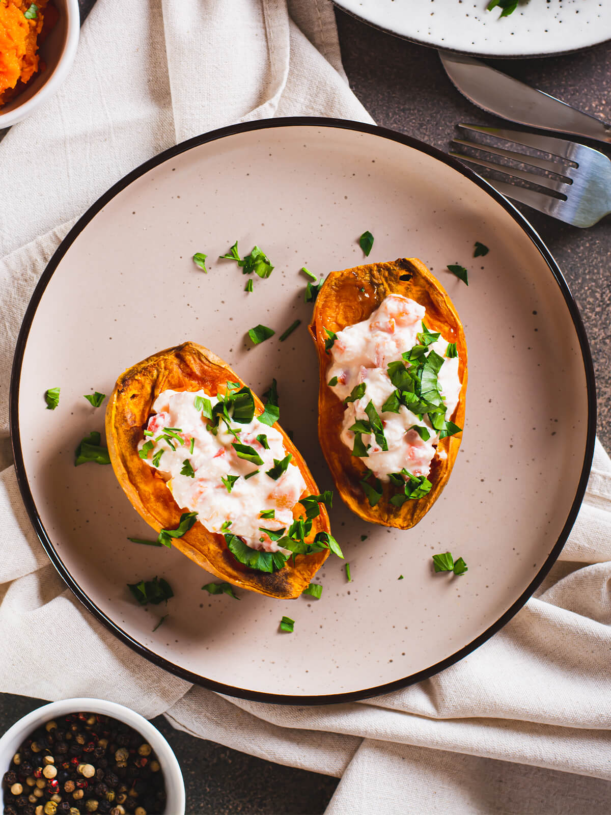 Zwei ausgehöhlte Süßkartoffel-Boote mit Ricotta-Tomaten-Creme und grober Petersilie