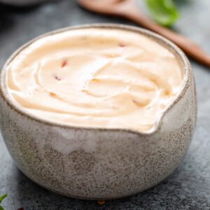 Cremiger Sweet Chili Dip in kleiner Schale mit roten Chili-Flecken