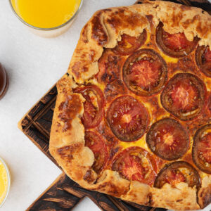 Tomaten-Galette mit geschmolzenem Cheddar und Tomatenscheiben in rustikalem Mürbeteig