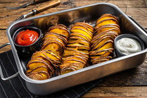 Gebackene Tornado-Kartoffeln am Holzspieß in einer Edelstahlschale mit Ketchup und Knoblauch-Kräuter-Dip
