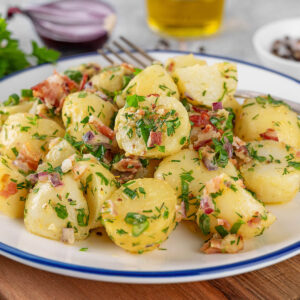 Warmer Kartoffelsalat mit Speck auf weißem Teller