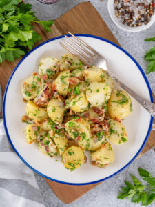 Nahaufnahme glänzender Kartoffelscheiben mit Speck und Kräutern