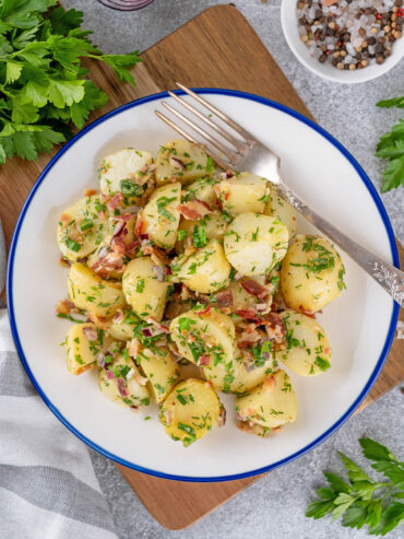 Nahaufnahme glänzender Kartoffelscheiben mit Speck und Kräutern