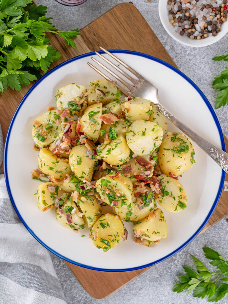 Nahaufnahme glänzender Kartoffelscheiben mit Speck und Kräutern