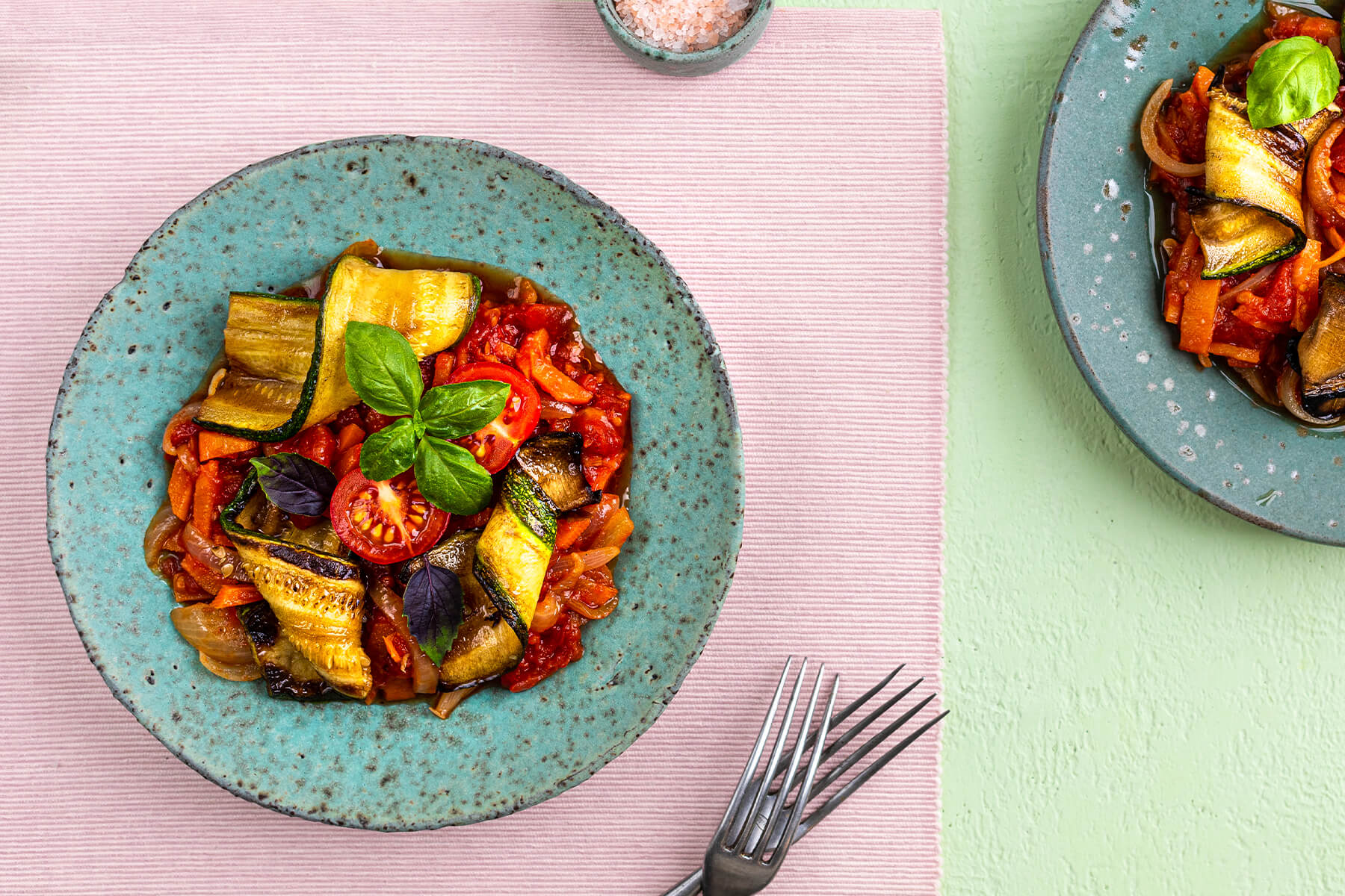 Teller mit gerösteter Zucchini-Gemüse-Pfanne, Cherrytomaten, roter Paprika und grünem und violettem Basilikum