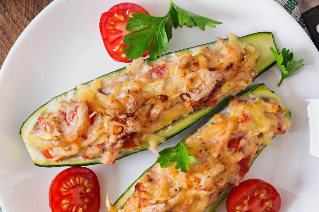 Gefüllte Zucchini-Schiffchen mit Käsekruste auf Teller