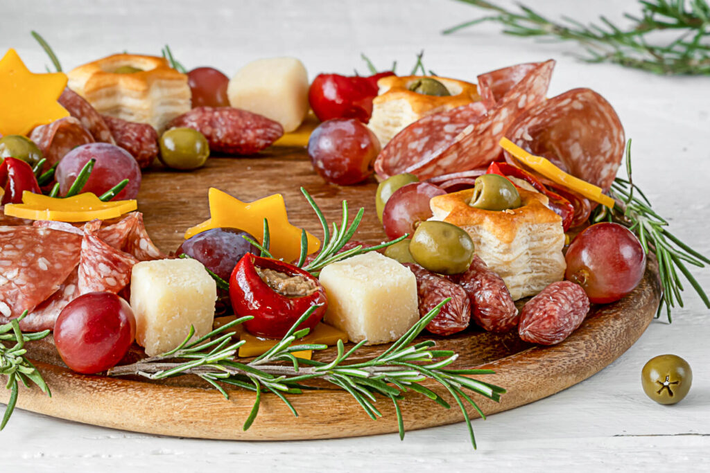 Nahaufnahme eines Ausschnitts des Antipasti-Kranzes mit Käsewürfeln, Trauben, Oliven und kleiner Salami