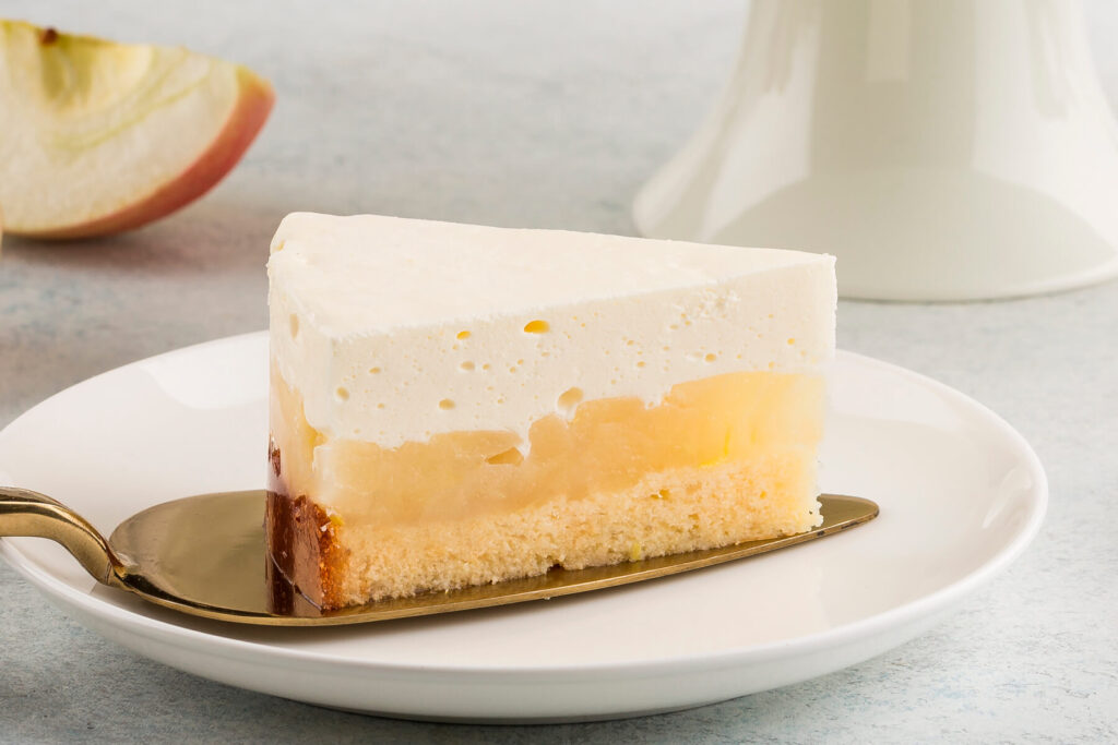 Apfel-Cheesecake-Stück mit Biskuitboden, Apfel-Gelee-Schicht und luftiger Frischkäse-Creme