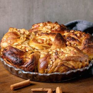 Apfel-Zimt-Pull-Apart-Brot in einer dunklen Keramikform auf einem Holzbrett