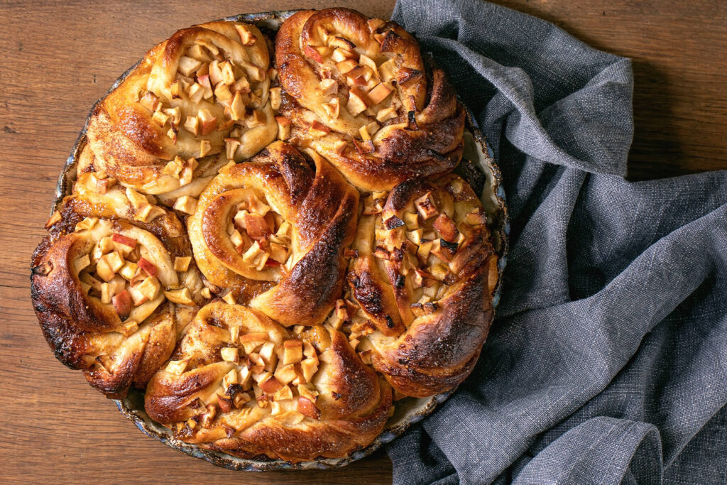 Fertig gebackenes Apfel-Zimt-Pull-Apart-Brot mit sechs Spiralen in der Keramikform von oben