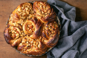 Fertig gebackenes Apfel-Zimt-Pull-Apart-Brot mit sechs Spiralen in der Keramikform von oben