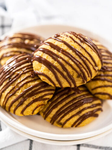 Stapel weicher Bananen-Cookies mit Schoko-Drizzle auf einem weißen Teller