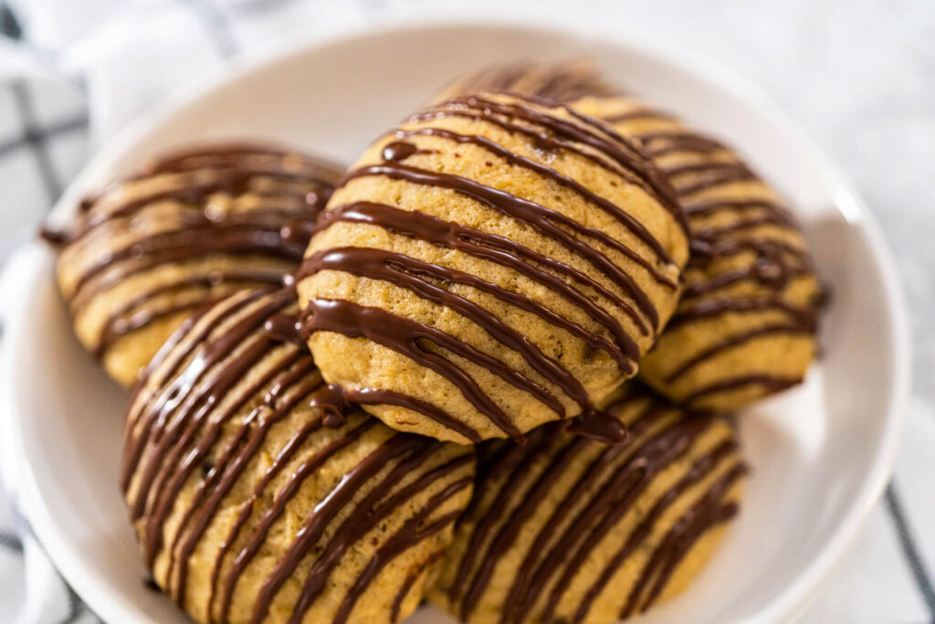 Weiche Bananen-Cookies mit Schoko-Drizzle auf einem weißen Teller angerichtet