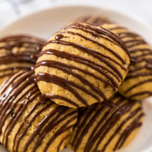 Weiche Bananen-Cookies mit Schoko-Drizzle auf einem weißen Teller angerichtet