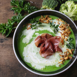 Brokkoli-Cremesuppe mit Serrano-Schinken-Rose, Sahne-Welle und knusprigen Zwiebel-Nestern