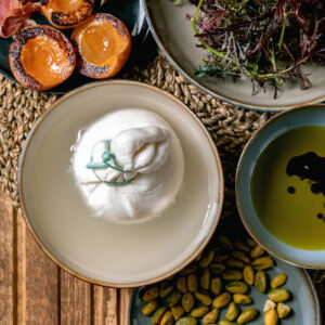 Burrata mit Aprikosen, Prosciutto, rotem Senfsalat, Olivenöl und Pistazien
